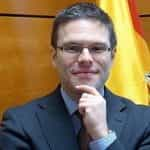 Juan Espinosa stands in an office in front of a Spanish flag.