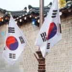 South Korea flags next to a traditional building.