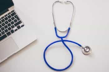 A doctor's stethoscope next to a laptop.