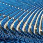 Multiple rows of blue seats at a large sports stadium.