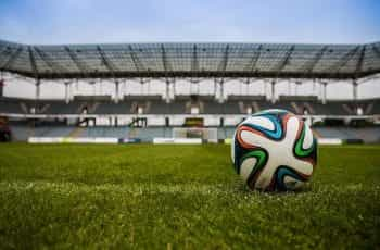 A football on a grass pitch in a stadium.