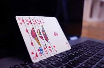 Several playing cards standing in a row and leaning against a laptop computer screen.