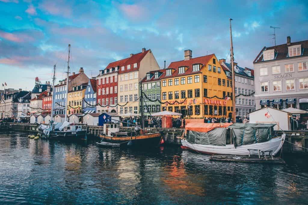 Boats docked at a harbor in front of colorful Nordic buildings