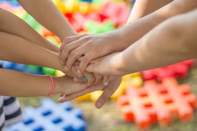 Several people’s hands coming together in unison in a sign of friendship.