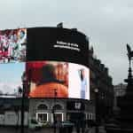 A corner of a building with large, lit advertisement displays.