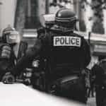 Black and white image of police in protective gear waiting at an event in Lyon, France.