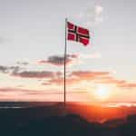 A flag hoisted on a rocky terrain against a sunset.